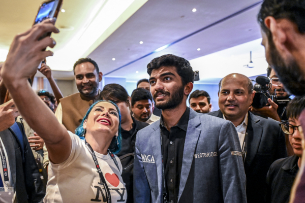 A fan takes a selfie with India's grandmaster Gukesh Dommaraju (C) after his win against China's chess grandmaster Ding Liren in game 14 of the 2024 FIDE World Championship in Singapore on December 12, 2024. The 18-year-old became "the YOUNGEST WORLD CHAMPION in history", said the International Chess Federation in a post on social media platform X, after Ding resigned in a thrilling endgame that had been expected to end in a draw. (Photo by Simon Lim / AFP) (Photo by SIMON LIM/AFP via Getty Images)