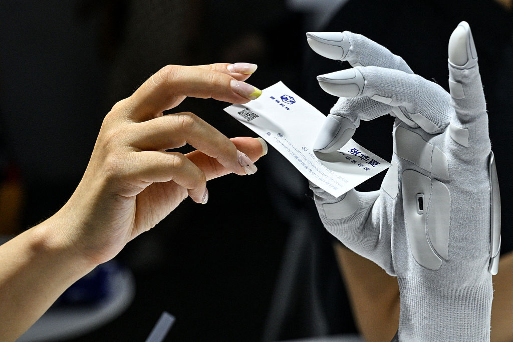 一名女子將一張名片遞給混合動力車駕駛機器人。(Hector Retamal/AFP via Getty Images)