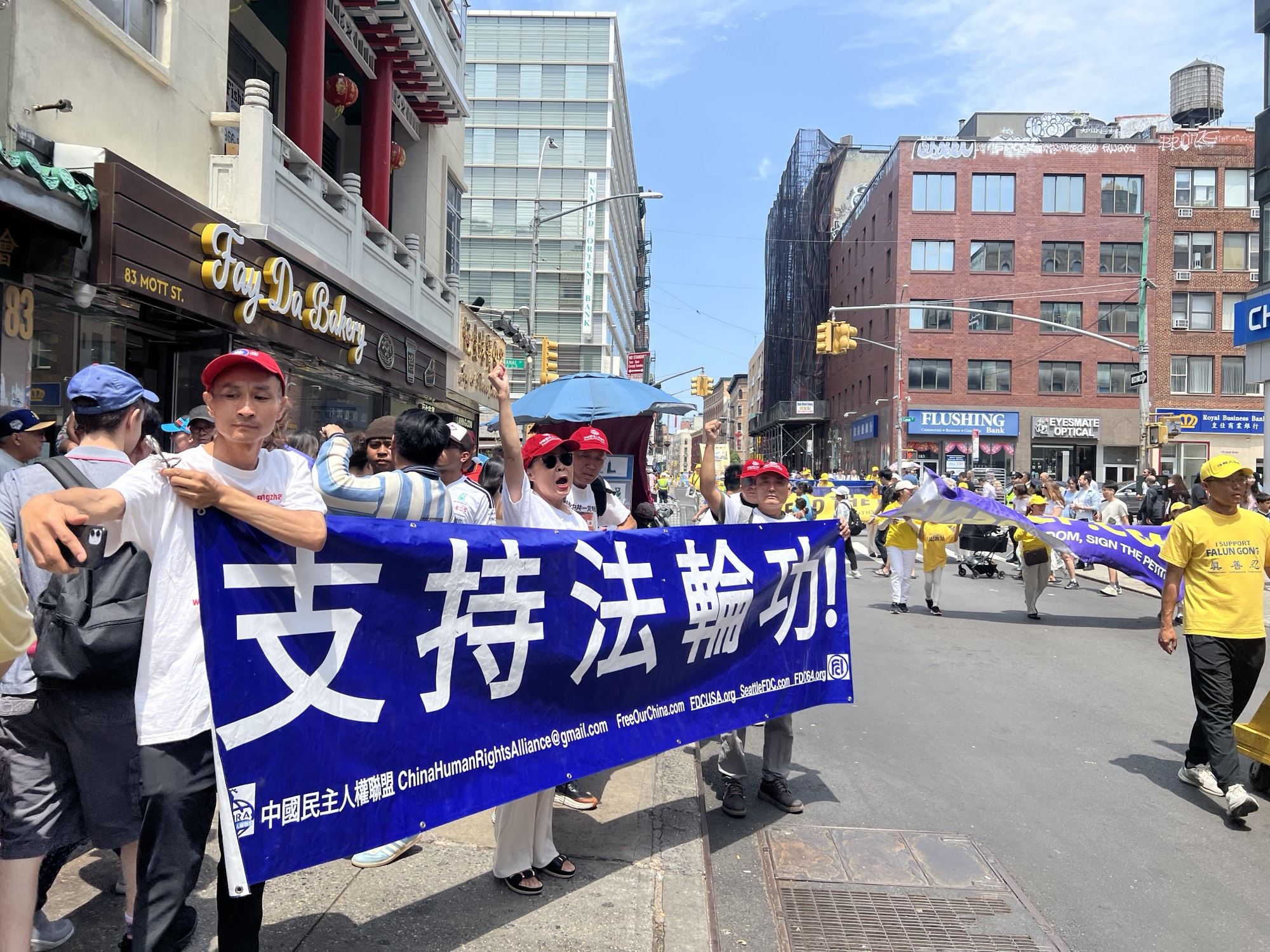 2026年7月19日，紐約法輪功學員遊行的路上，有多位華人民眾自發地打出橫幅前來聲援法輪功學員。趙女士（中間喊口號）受訪時表示中共就是撒旦。（施萍／大紀元）