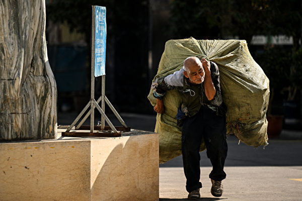 圖為雲南省西部瑞麗市一名背著回收材料的老人。(Noel Celis/AFP)